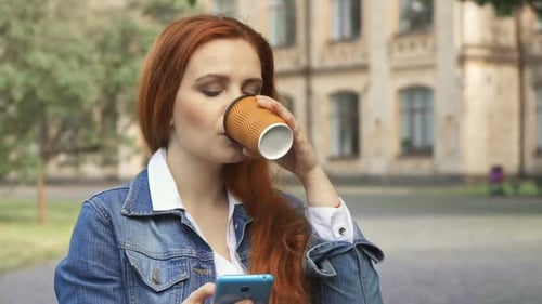 Woman Using Smartphone and Drinking Coffee Outside