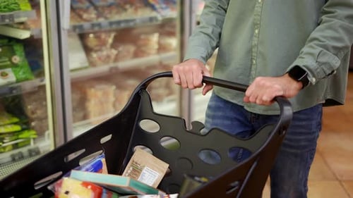 Unrecognizable Man Walking with Shopping Cart in Supermarket