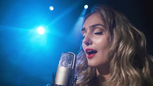 Woman Sings into Microphone Under Blue Lights