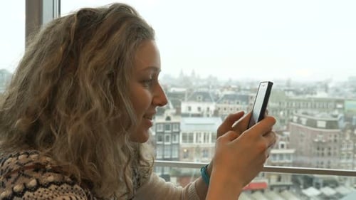 Woman Using Smartphone With City View
