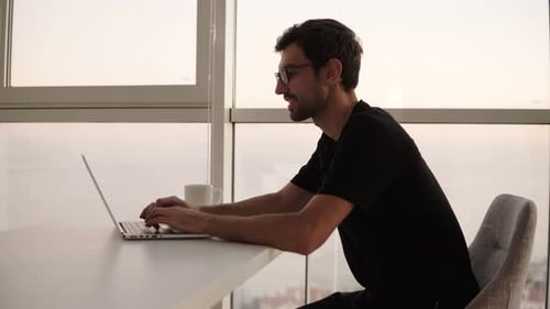 Seitenansicht eines Geschäftsmannes, der einen Laptop am entfernten Arbeitsplatz in Zeitlupe benutzt