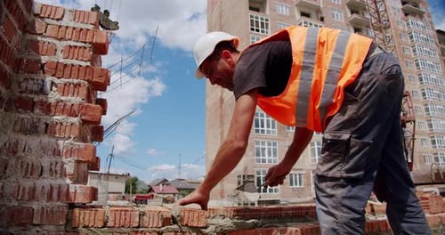 Um trabalhador da construção civil coloca argamassa e começa a colocar tijolos para construir uma casa