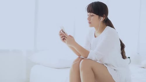 Woman Using Phone on Bed in Bright Room
