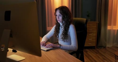 Un estudiante sentado frente a una pantalla de computadora a altas horas de la noche escribe su tesis de licenciatura