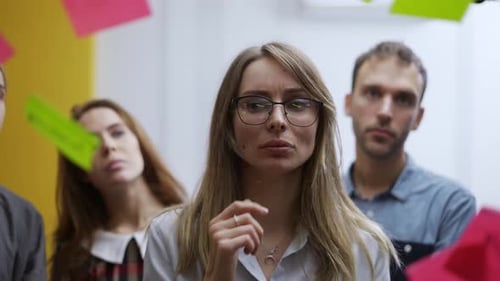 Confused Businesswoman on Team Meeting Sticks the Color Note on Glass Wall
