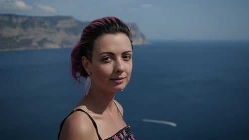 Girl with Purple Hair Smiles at the Camera Against the Backdrop of the Sea Bay