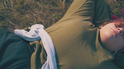 Overweight Girl with Sunglasses Rests on Grass at Campsite