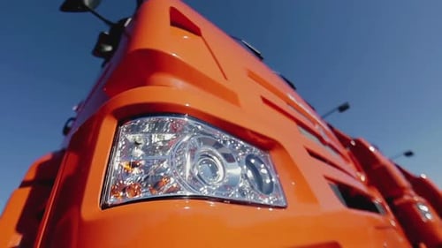 Bright Orange Semi-Truck Cab Against Blue Sky