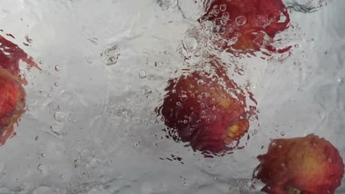 Fresh Red Apples Falling into Clear Water