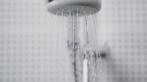 Water Flowing From a Shower Head in Bathroom