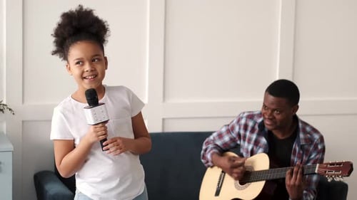 Child Singing with Guitar Accompaniment Indoors