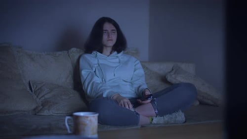 Teenage Girl Watches TV in Darkened Living Room