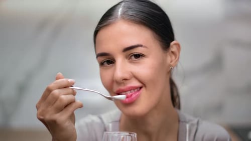 Smiling Woman Eating with Spoon, Close Up