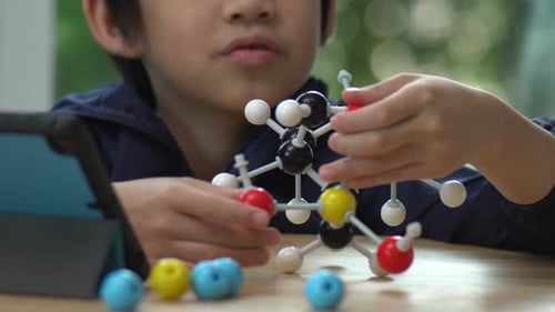 Close Up Of Asian Child Constructing Molecular Model In Science Classroom