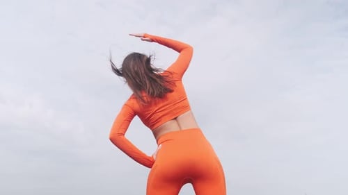 Back view. Strong muscular woman goes in for sports outdoors. Healthy adult woman in sportswear doin