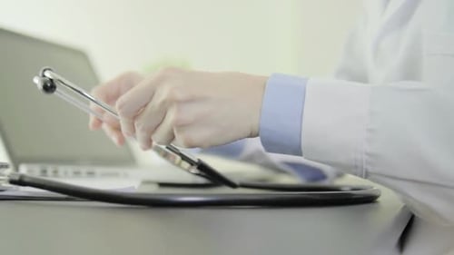 Doctor Assembling Stethoscope at Desk with Laptop