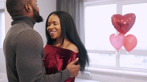 Loving Couple Embrace with Heart Balloons Indoors