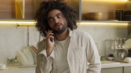 Young Man Talking on Phone in Modern Kitchen