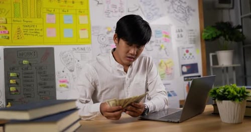 Young Adult Counts Cash in Office