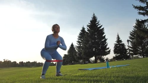Woman Exercising with Resistance Band in Park