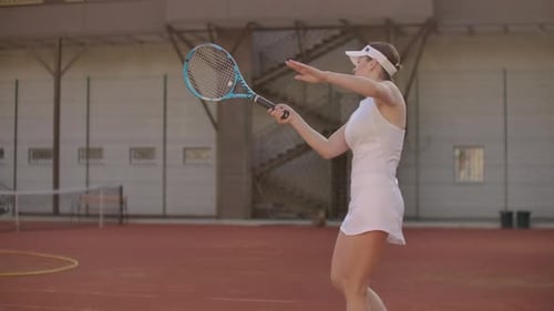 Woman Hits Tennis Ball on Court During Sunny Day