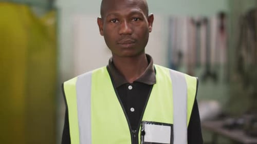 African American male factory worker at a factory wearing a high vis vest