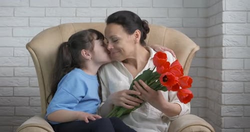 Child Giving Flowers to Adult in Armchair