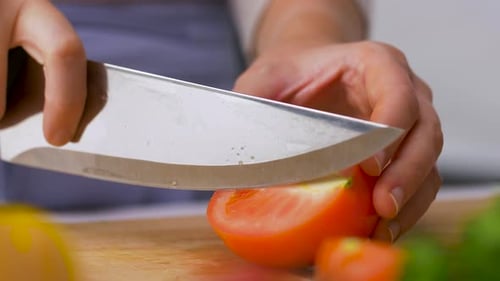 Hands Slicing Fresh Red Tomato with Sharp Knife