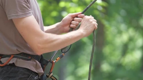 Man Belays His Partner Climber with Belaying Device and Rope