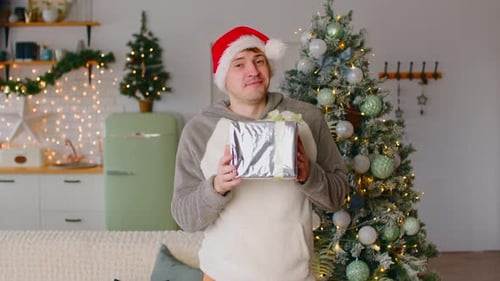 Man in Santa Hat Holding Christmas Gift