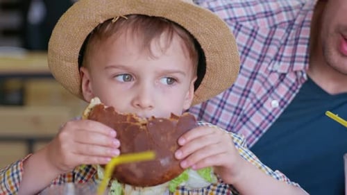 Child Enjoying a Burger at an Urban Restaurant