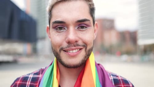 Person Smiling with Pride Flag in Urban Setting