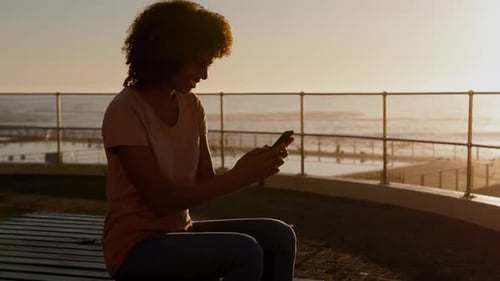 Woman Using Mobile Phone at Beach During Sunset