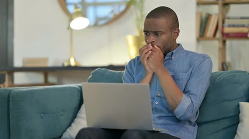 Man Reacting to Laptop News on Couch