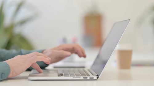 Hands Typing on Laptop in Bright Workplace