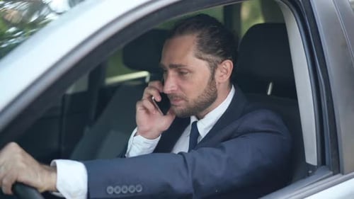 Man Talking on Phone Inside Car Wearing Suit
