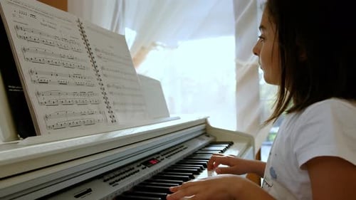 Girl Plays Piano Indoors During the Daytime