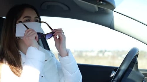 Woman Wearing Face Mask Puts on Sunglasses in Car