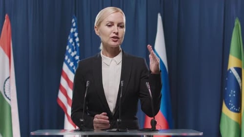 Woman Speaking at Podium with Flags Background
