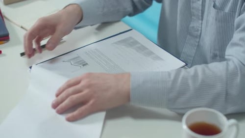 Office Worker Examines Documents and Graphics