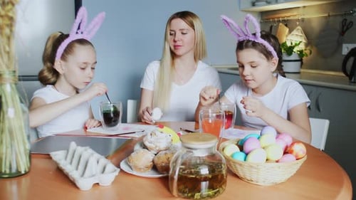 A Mother and Her Daughters Painting Easter Eggs
