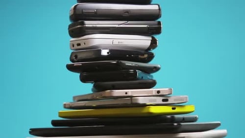Stacked Pile of Mobile Phones on Teal Background