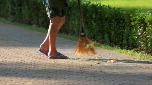 Un concierge balaie les feuilles du parc.