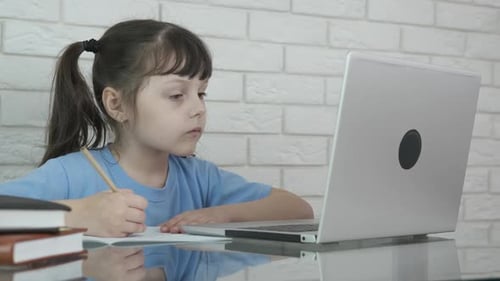 Child Learning Online Using Laptop and Taking Notes