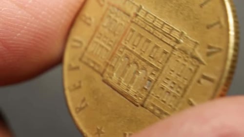 Close Up of a Golden Coin Being Held