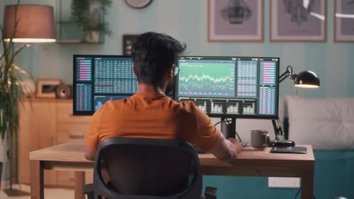 Man Works With Stock Data on Monitors