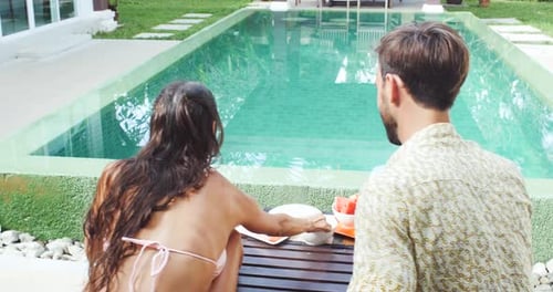 Couple Eating Fruit Together by the Poolside