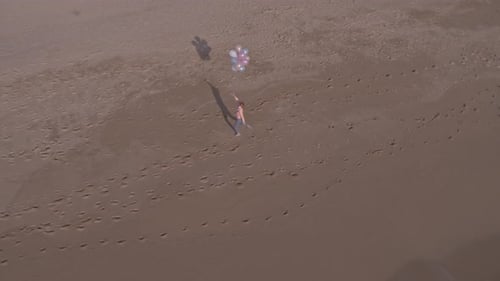 Woman Runs with Balloons on Sandy Beach Aerial