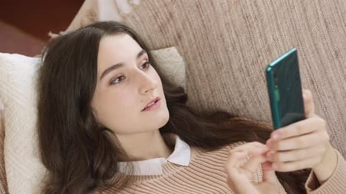 Woman Using Phone While Lying on Couch