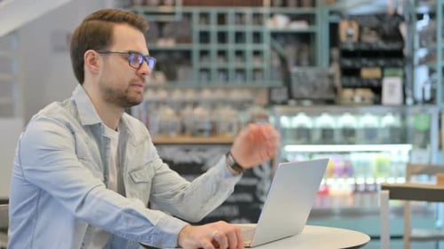 Man Working on Laptop at Cafe Table